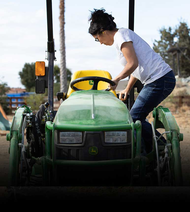Woman getting in the seat of riding lawn equipment