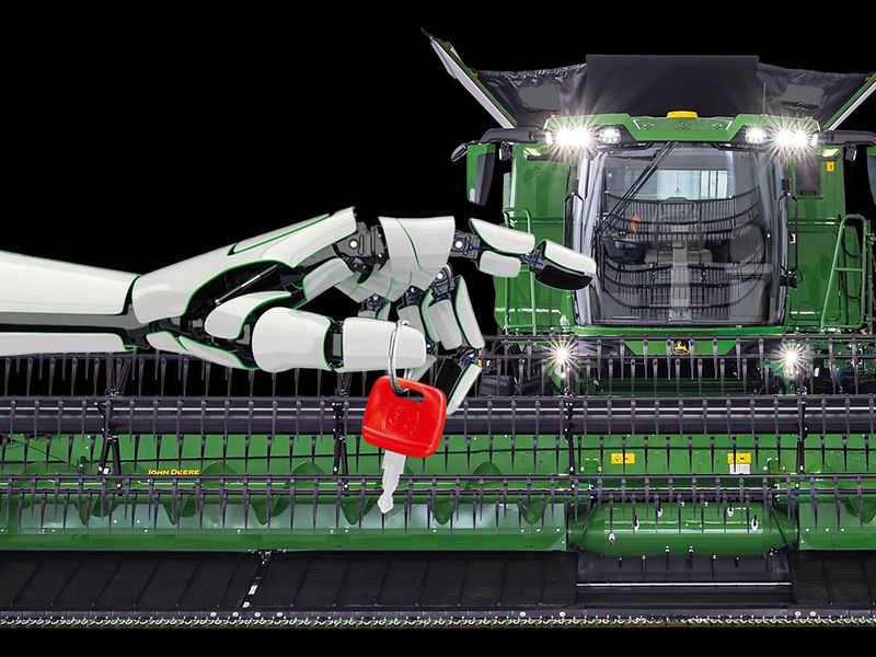 Robot hand holding red key in front of combine, symbolizing advanced agricultural technology.